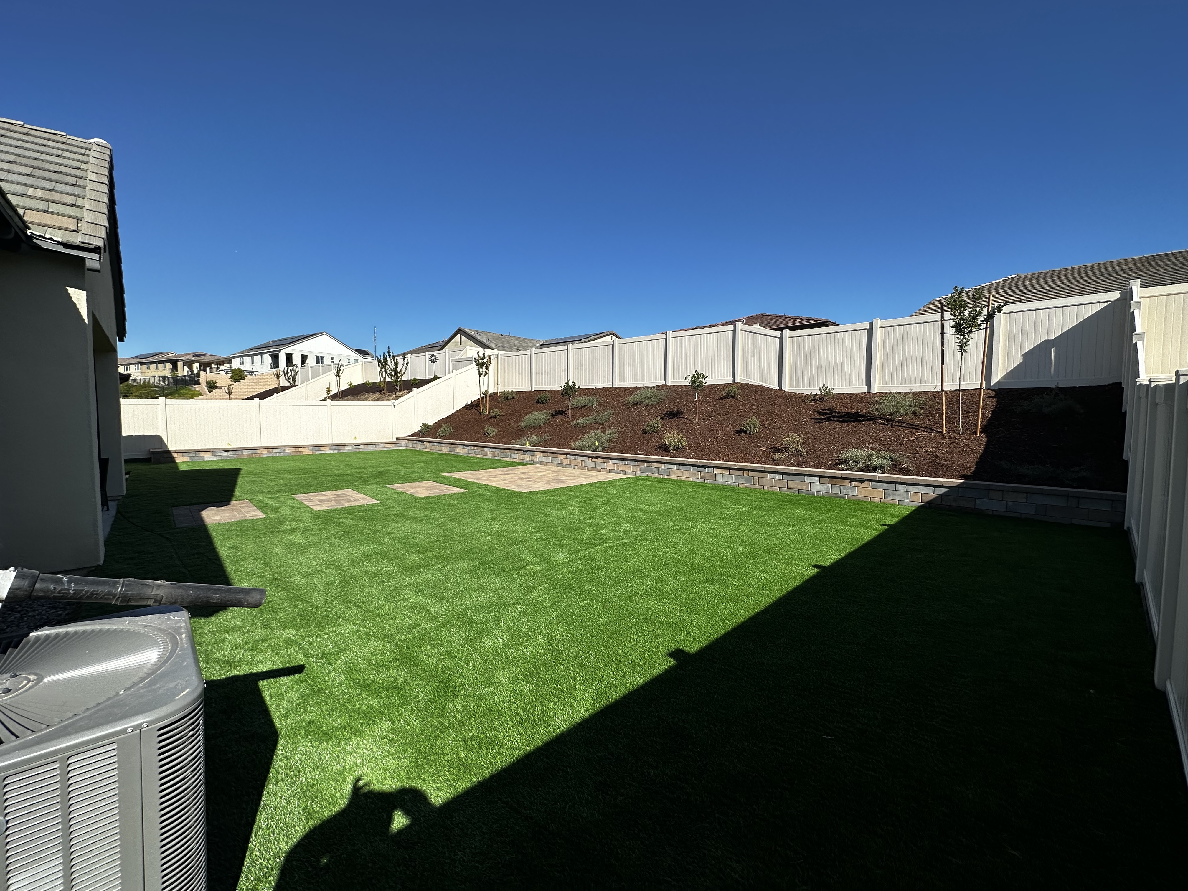 Backyard artificial turf with retaining wall and vinyl fencing