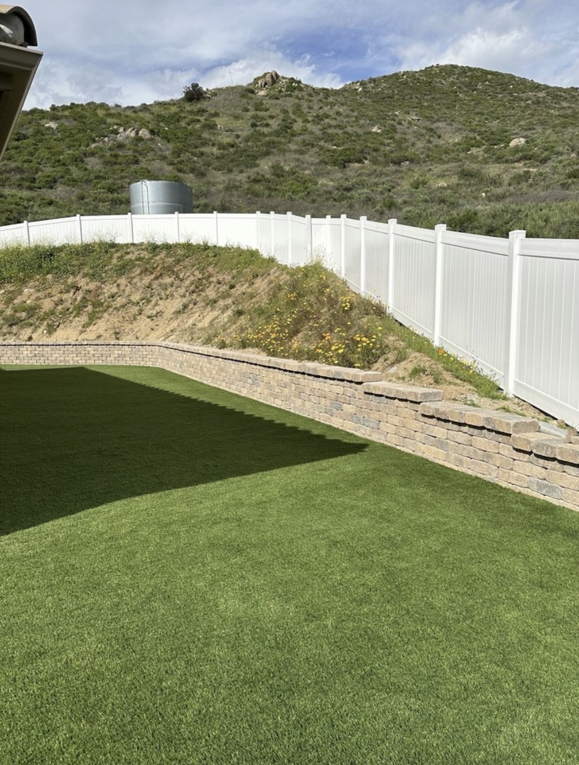 Retaining wall with artificial turf and vinyl fencing