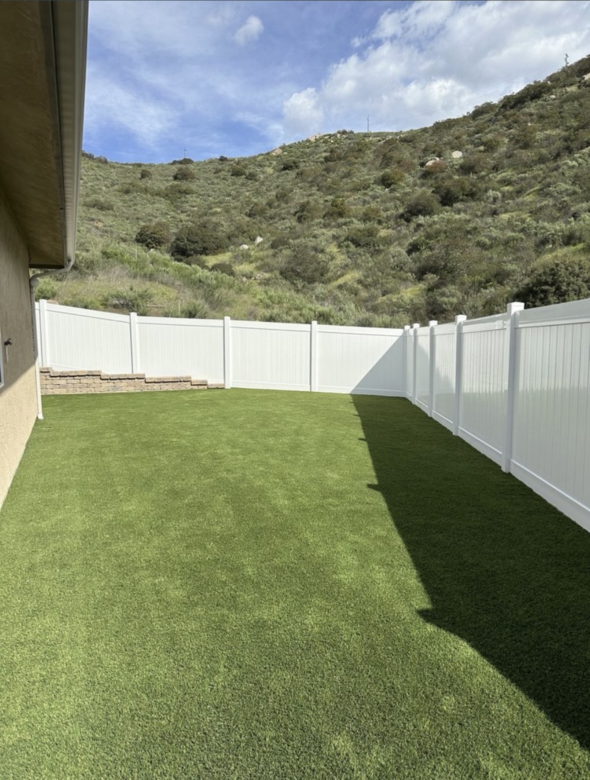 Vinyl fence with artificial turf and hillside view